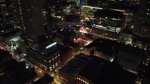Aerial push-in shot of busy, vibrant downtown Toronto at night. View around the illuminated David Pecaut Square. Drone flying over modern skyscrapers around the financial district with busy traffic.