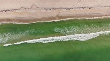 Overhead view of a couple walking on a bright, sandy beach in the summer.