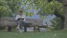 Young woman reads and studies her Bible outside on a bench