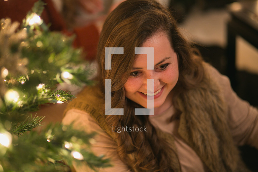 A smiling woman near a Christmas tree.