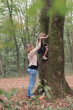 mother helping her daughter climb a tree