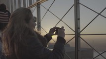 people taking pictures off of a skyscrapers rooftop balcony 