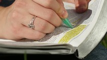 Hand highlighting a passage in the Bible.