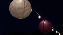 paper lanterns and a string of lights at night 