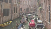 The atmosphere of narrow canals in the city of Venice, with many bridges and small boats parked.