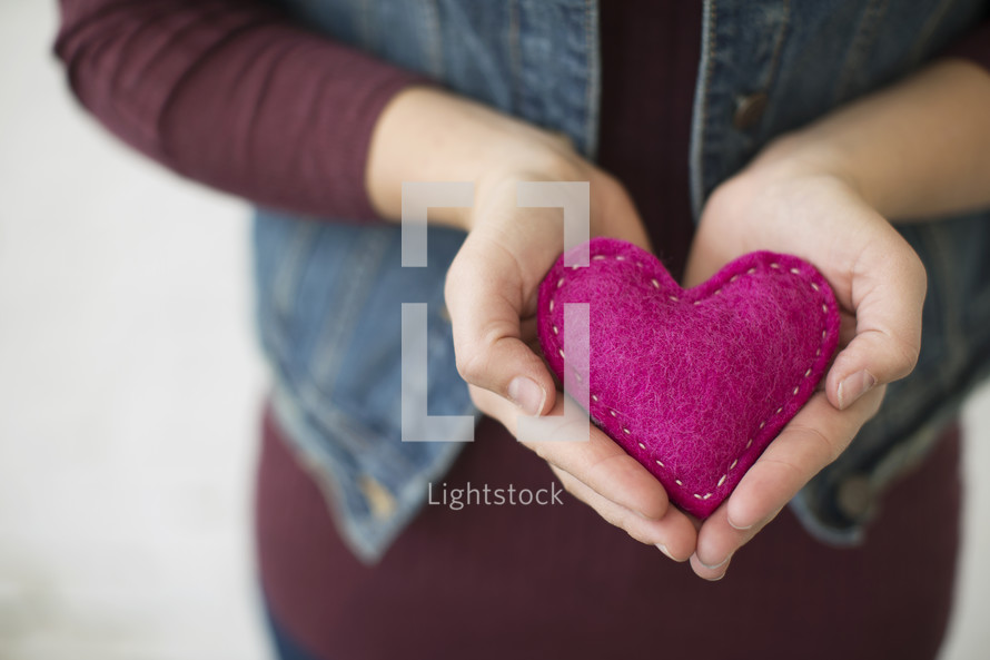 a woman holding a pink felt heart 