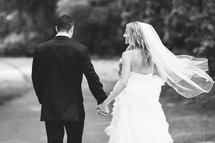 bride and groom walking holding hands outdoors