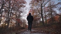 Unrecognizable Man with Black Jacket Walking on Autumn Fall Foliage Tree Alley during Sunset Slow Motion