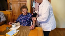 A nurse checking blood pressure on an elderly woman at a care home