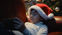 Little boy with Christmas hat playing videogame