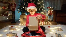 Boy opening Christmas gift under the tree
