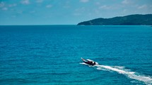 Wooden boat in turquoise sea, movement on blue water. Trip boat with tourists sailing on clean blue sea surface. A long-tailed Thai boat sails among the islands, touristic excursion ride. Aerial. 