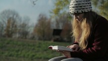 a teen girl sitting on a bench reading a Bible 