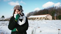 Girl freezing in the mountain with house in the background