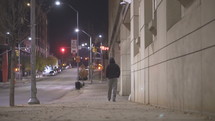 a man walking on a city sidewalk alone at night 