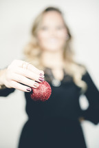woman holding a red Christmas ornament 