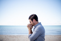 man praying on a beach 