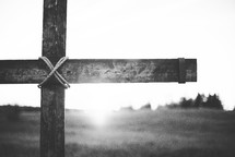 wooden cross in a field at sunset 