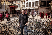 man with a camera surrounded by pigeons in Tibet 