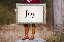 a woman holding a sign the reads joy 