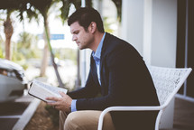 man sitting outdoors reading a Bible 