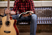 man with a guitar reading a Bible 
