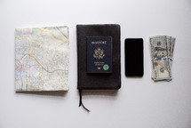 map, passport, Bible, cellphone, and cash on a white background 