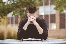 a man praying over an opened Bible 