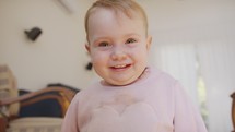 Cute baby girl playing at home and smiling to the camera