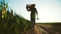 Farmer walks to field and inspects his land with shovel and basket for harvest fresh crops planted. Agricultural production of natural healthy eat. Growing and selling large volumes of products.