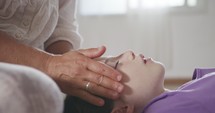 Shiatsu treatment. Masseuse giving gentle face treatment to a little girl