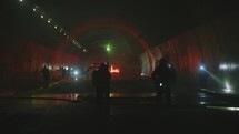 Car accident scene inside a tunnel, firefighters rescuing people from cars