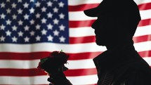 Silhouette of Usa Soldier holds flowers