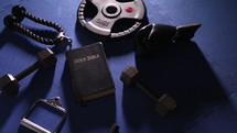 Bible and weights on a gym mat 