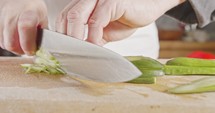 Slow motion close up of a chef knife slicing a cucumber