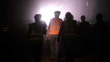 silhouette of many construction workers walking out from a large tunnel