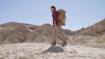 man backpacking through a desert 