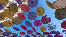 colored umbrellas hanging in the streets of the city