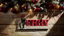 Hands putting Merry Christmas sign on wooden background