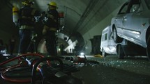 Car accident scene inside a tunnel, firefighters rescuing people from cars