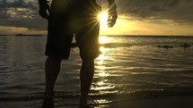 man walking on a beach in shallow water 