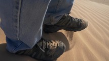Close up of a man walking on a sand dune in slow motion