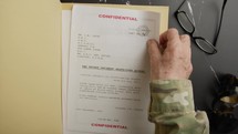 Militar man reading Top Secret Documents On Table