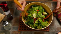 A woman tossing a fresh salad before dinner