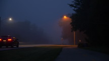 A lone car passing by on a foggy morning