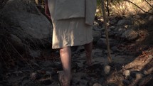 Low tracking shot of Jesus or a Bible prophet walking in the desert wilderness