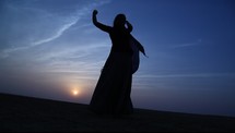 woman with a scarf dancing in the desert 