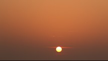 The sun low on the horizon in a hazy sky.