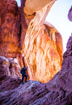 man with a camera standing in a red rock arch 