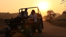 men in a Jeep on a dirt road in India at sunset